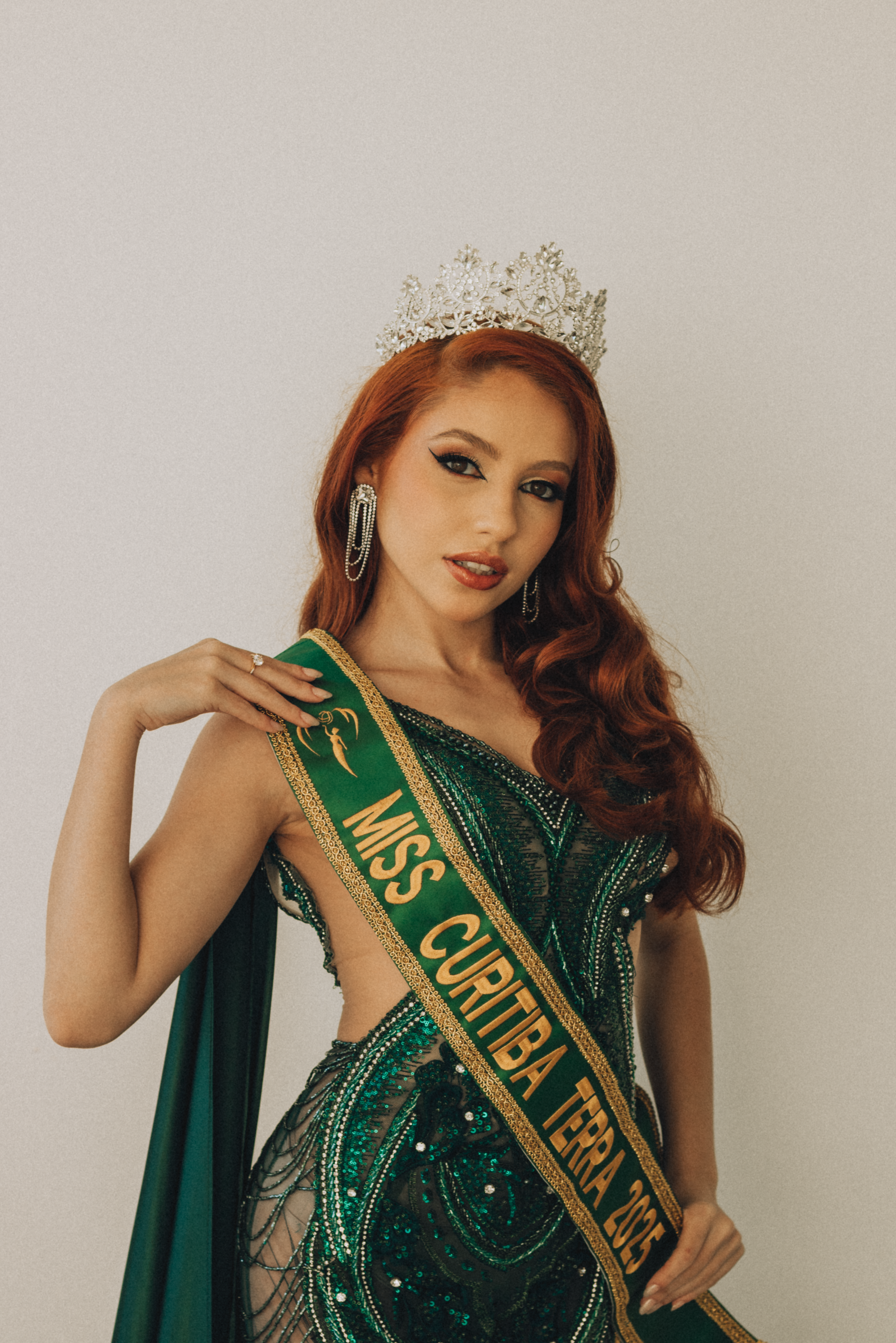 A beautiful pageant winner wearing a crown and sash 'Miss Curitiba'.