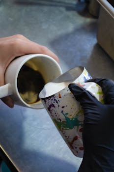 Barista skillfully pours milk for latte art in a Tepic café, Mexico.