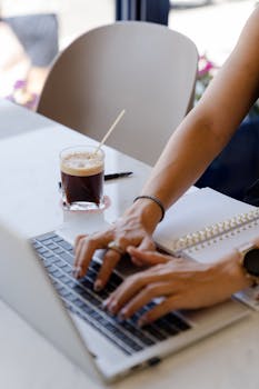 A woman typing on a laptop with a cup of coffee on the table, symbolizing remote work.