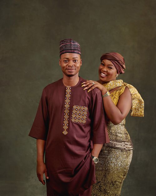 Free Happy African couple posing in elegant traditional attire against a studio backdrop. Stock Photo