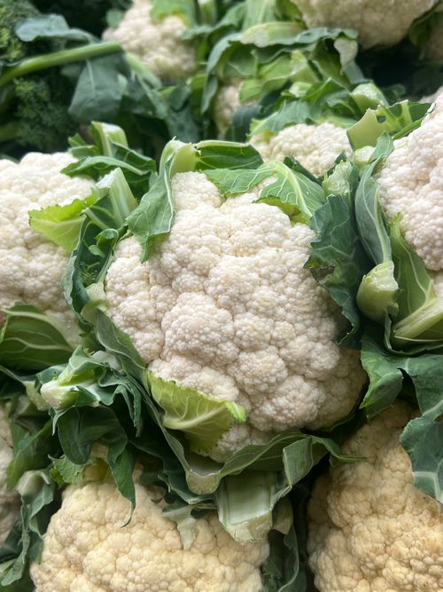 Free A vibrant close-up of freshly harvested organic cauliflower with lush green leaves. Stock Photo