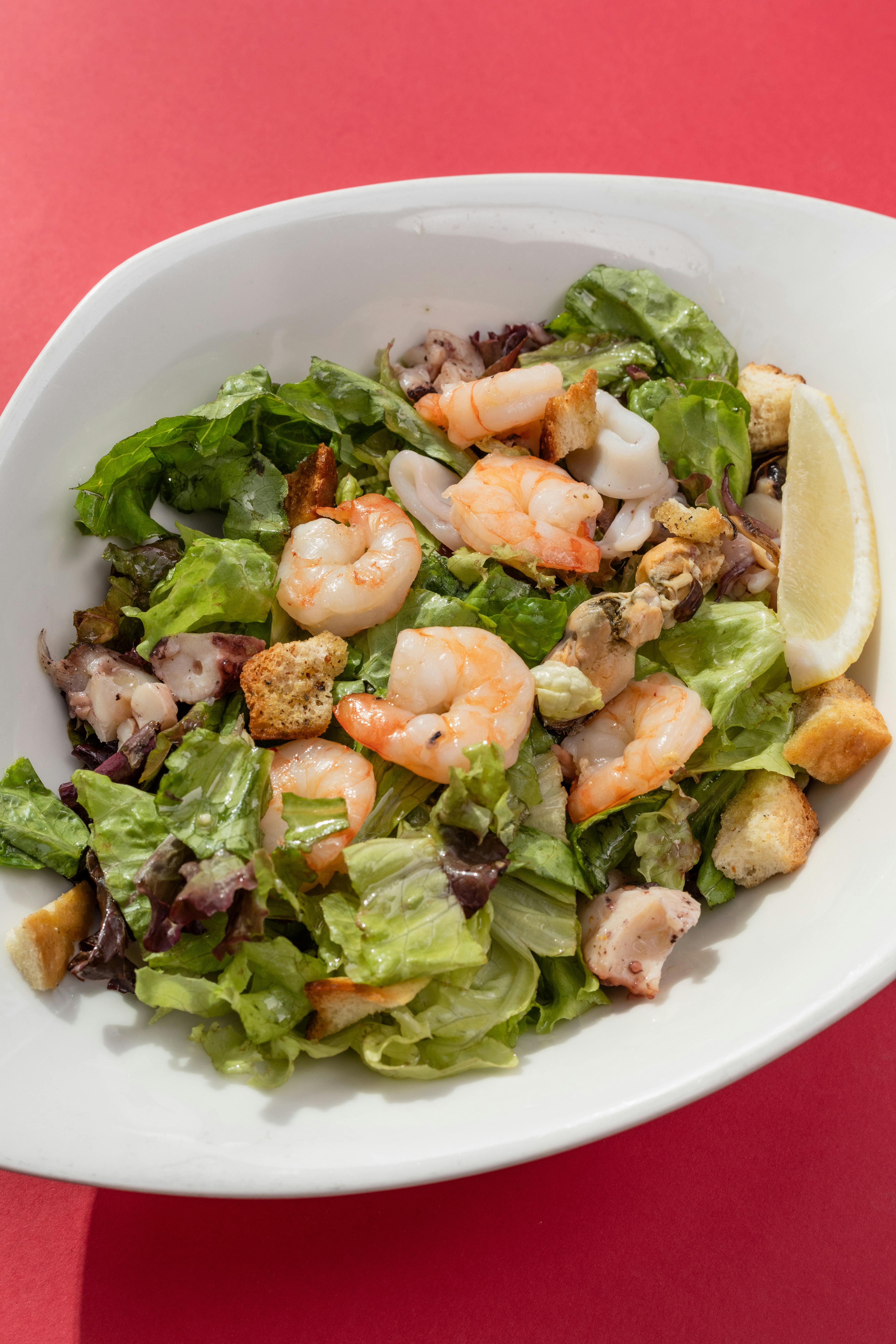 Insalata di mare con gamberi, lattuga, crostini e fetta di limone