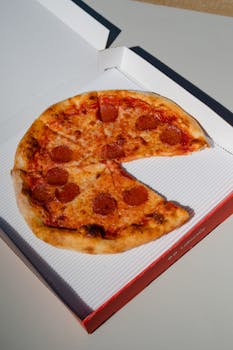 Delicious pepperoni pizza with melted cheese in an open cardboard box ready to eat.
