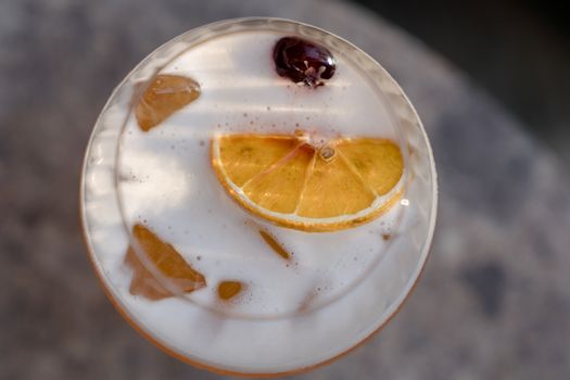 A frothy cocktail garnished with an orange slice and cherry, perfect for refreshing moments.