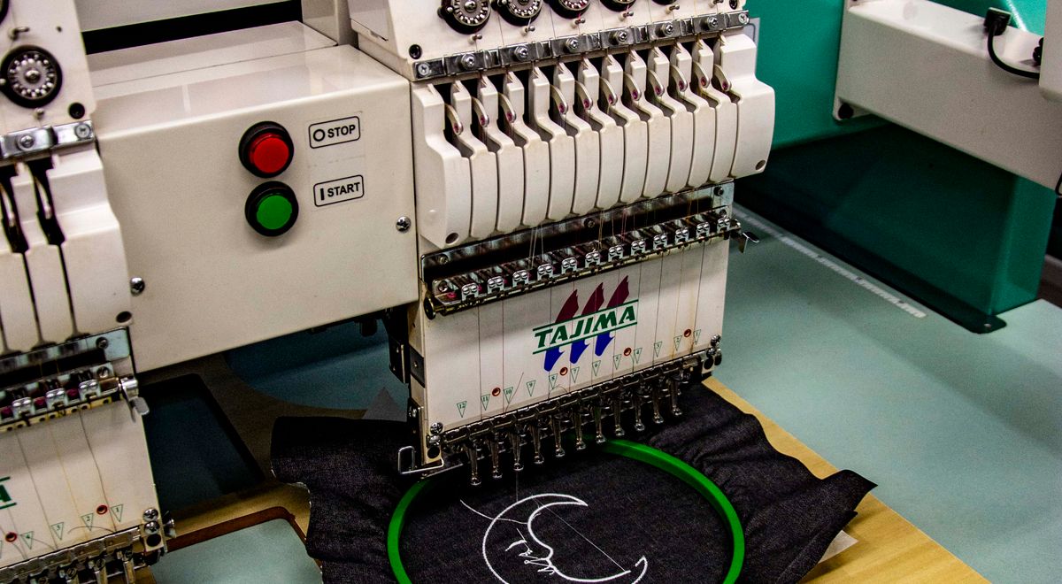 Machine à broder professionnelle cousant un logo sur un tablier sombre en gros plan