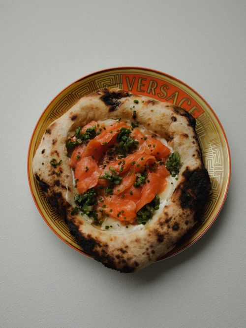 Free Smoked salmon pizza with greens on a designer Versace plate. Stock Photo