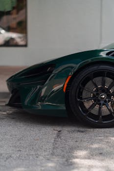Close-up of a luxury car's front wheel on a city street during the day.