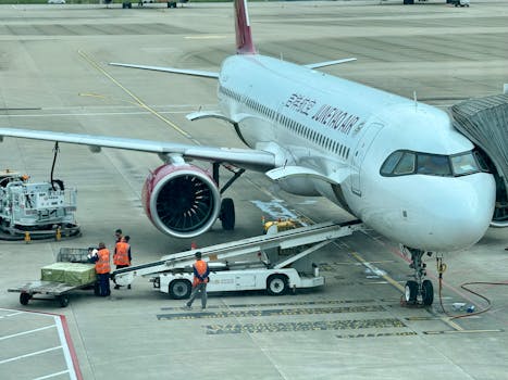 Airplane being loaded with cargo at the airport terminal with ground crew.