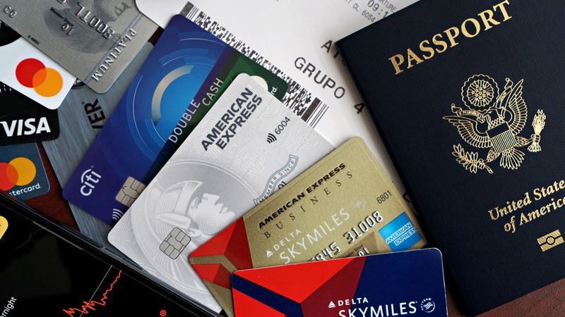A collection of travel essentials including a passport, credit cards, and a boarding pass.