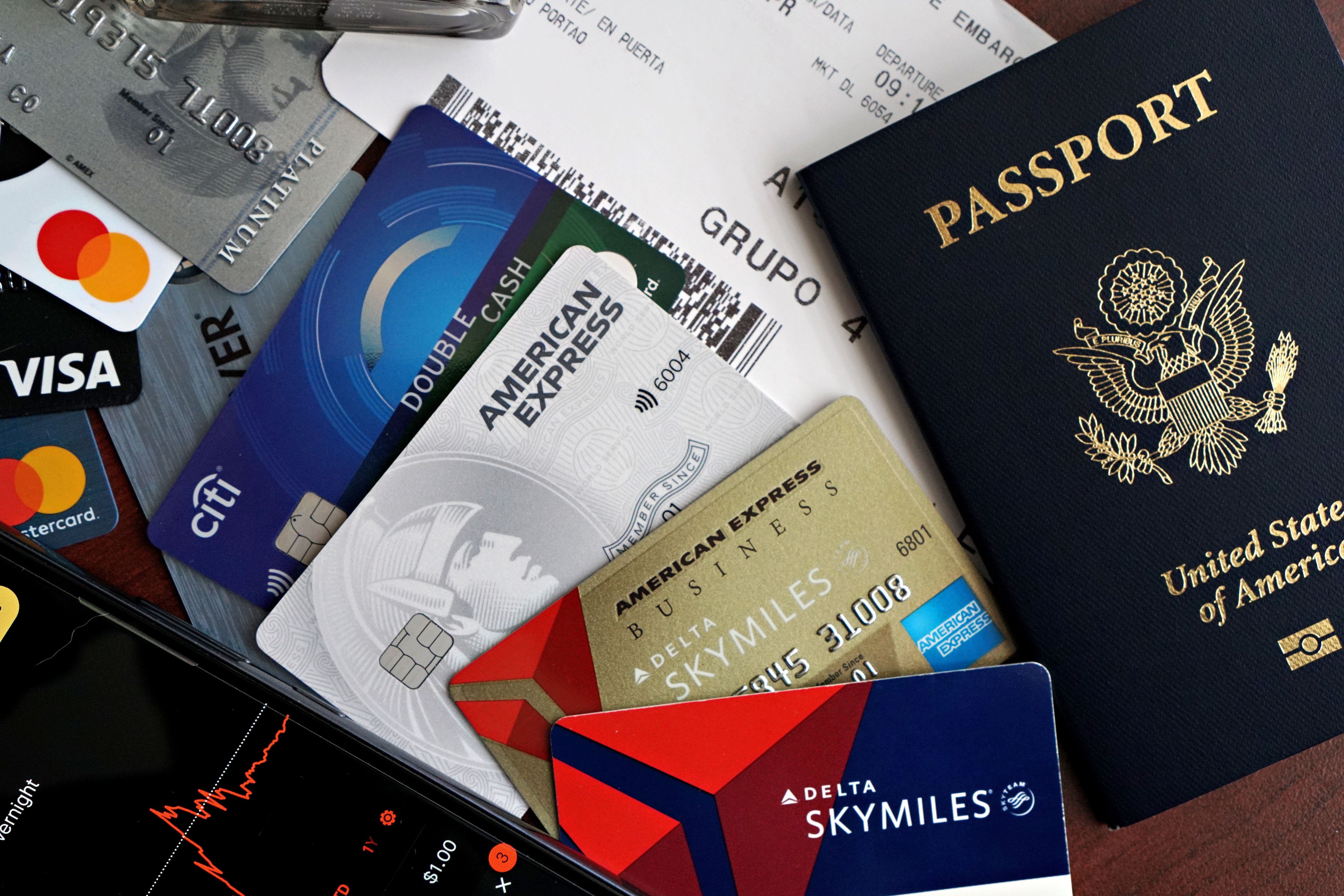 Travel essentials including passport, credit cards, and a boarding pass laid out on a table