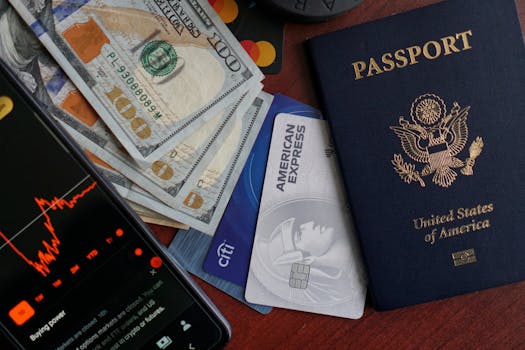 Top view of US passport, credit cards, cash, and phone showing financial graph, ideal for travel themes.