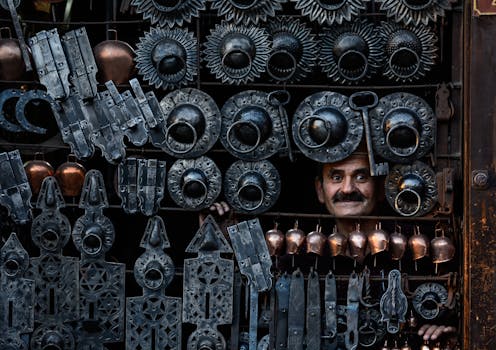 A craftsman peeks through traditional ironwork on display at a market in Safranbolu, Türkiye.