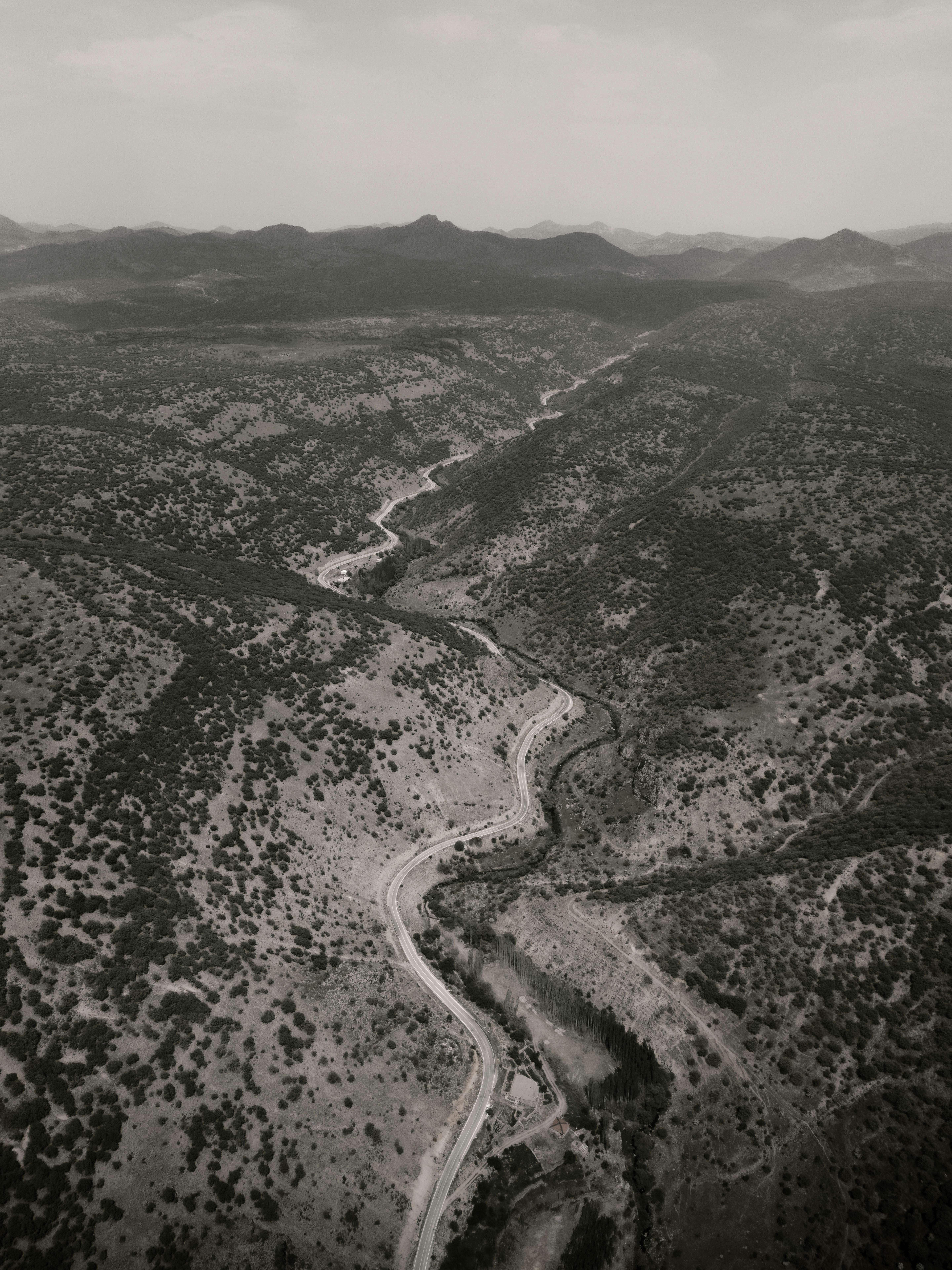 Black and white aerial shot of a winding road through a rugged Turkish landscape.