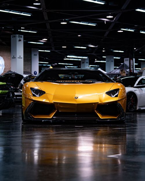 Free A striking yellow luxury sports car showcased in an indoor event. Stock Photo