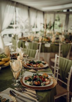 A beautifully arranged wedding reception table with green decor, showcasing a variety of delectable dishes.