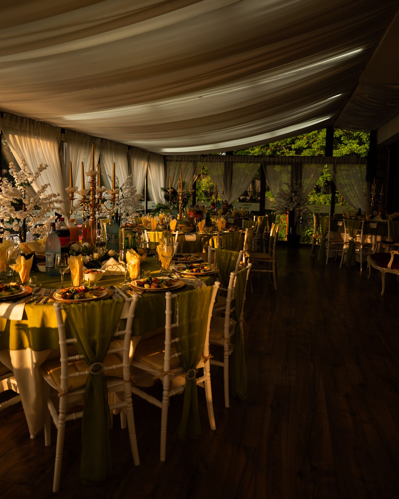Wedding reception beneath layered ivory ceiling draping and warm lighting