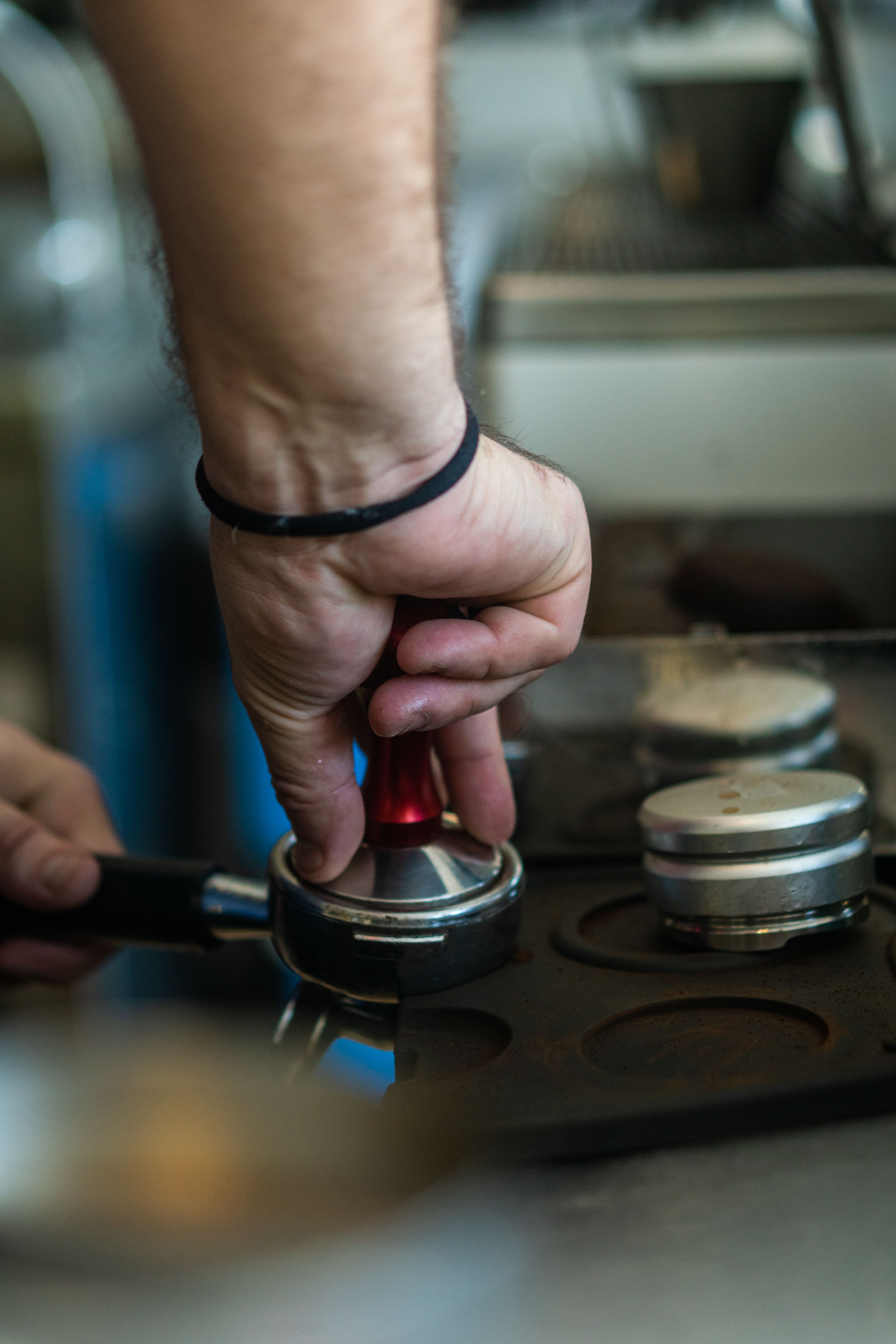 Barista pressing espresso grounds in portafilter · Free Stock Photo