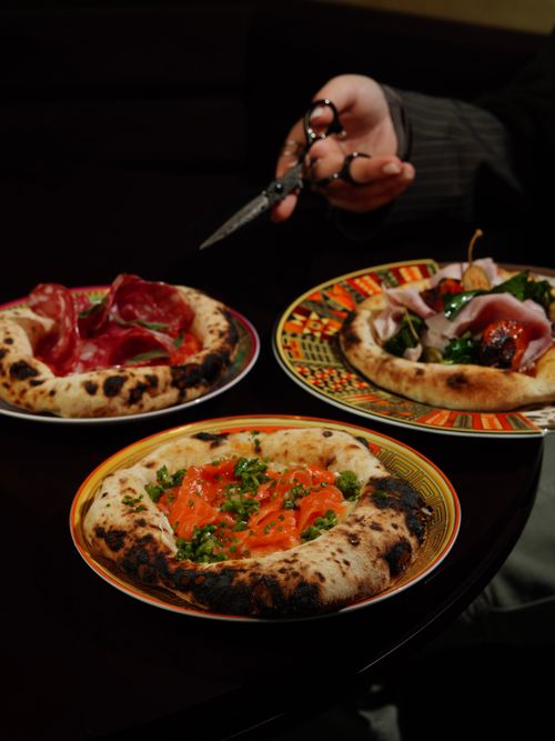 Free Delicious variety of pizzas presented stylishly on colorful plates. Perfect for food lovers. Stock Photo