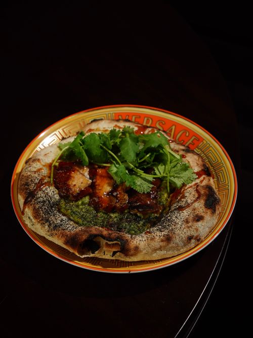 Free Delicious gourmet pizza topped with fresh cilantro served on an elegant designer plate. Stock Photo