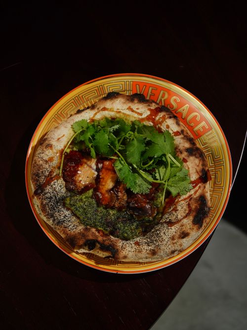 Free Gourmet pizza with herbs served on a stylish Versace plate. Stock Photo