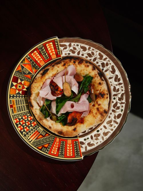 Free Delicious gourmet pizza garnished with fresh ingredients on a decorative plate. Stock Photo