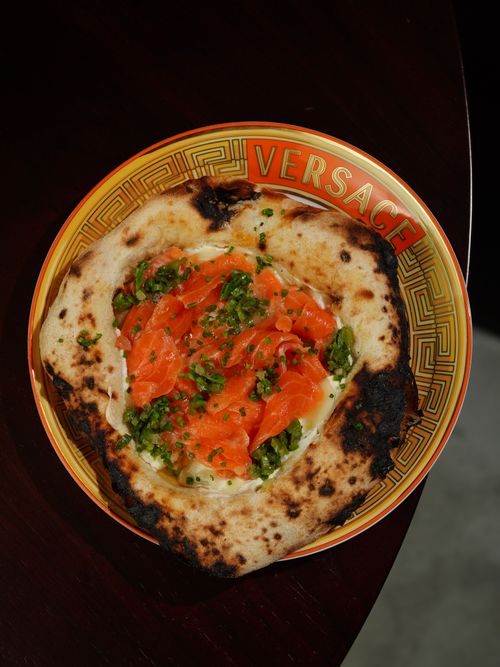 Free Gourmet pizza with smoked salmon and greens served on a Versace plate. Stock Photo