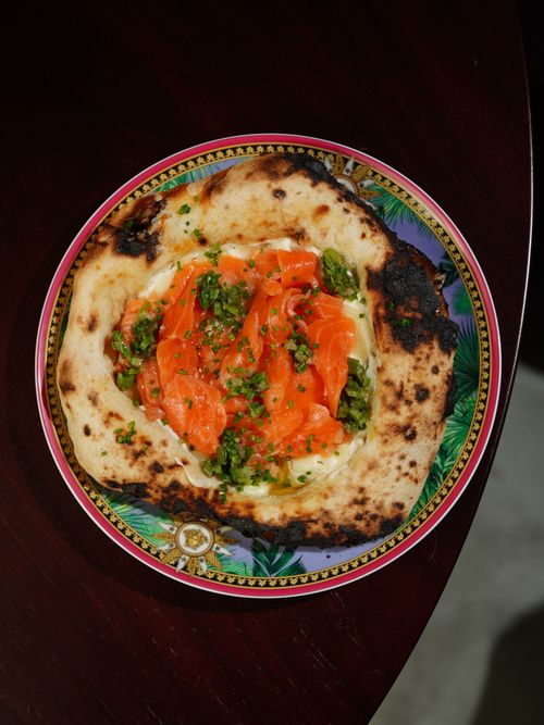 Free Delicious gourmet pizza topped with smoked salmon and fresh herbs on a decorative plate. Stock Photo