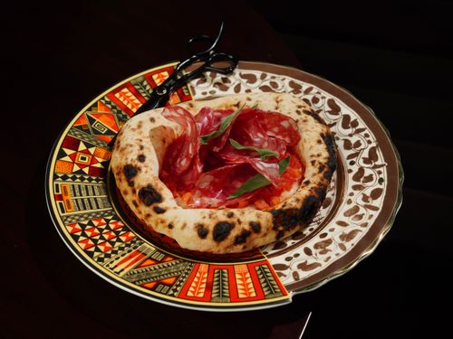 Free Close-up of artisanal pizza topped with salami on an ornate plate. Stock Photo