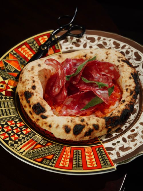 Free Artisan pizza topped with salami on a decorative plate. Perfect for food enthusiasts. Stock Photo
