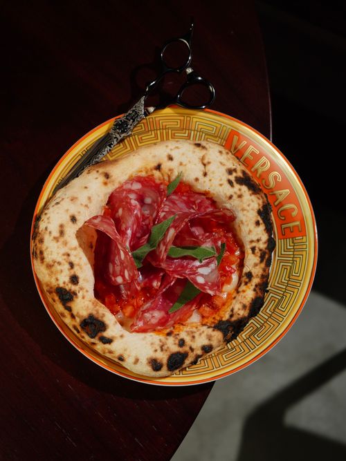 Free Delicious pizza with salami and arugula on an iconic Versace plate. Stock Photo