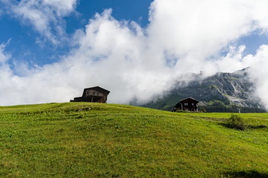 Idyllic alpine landscape featuring cabins on green hills under a vibrant sky in Switzerland.