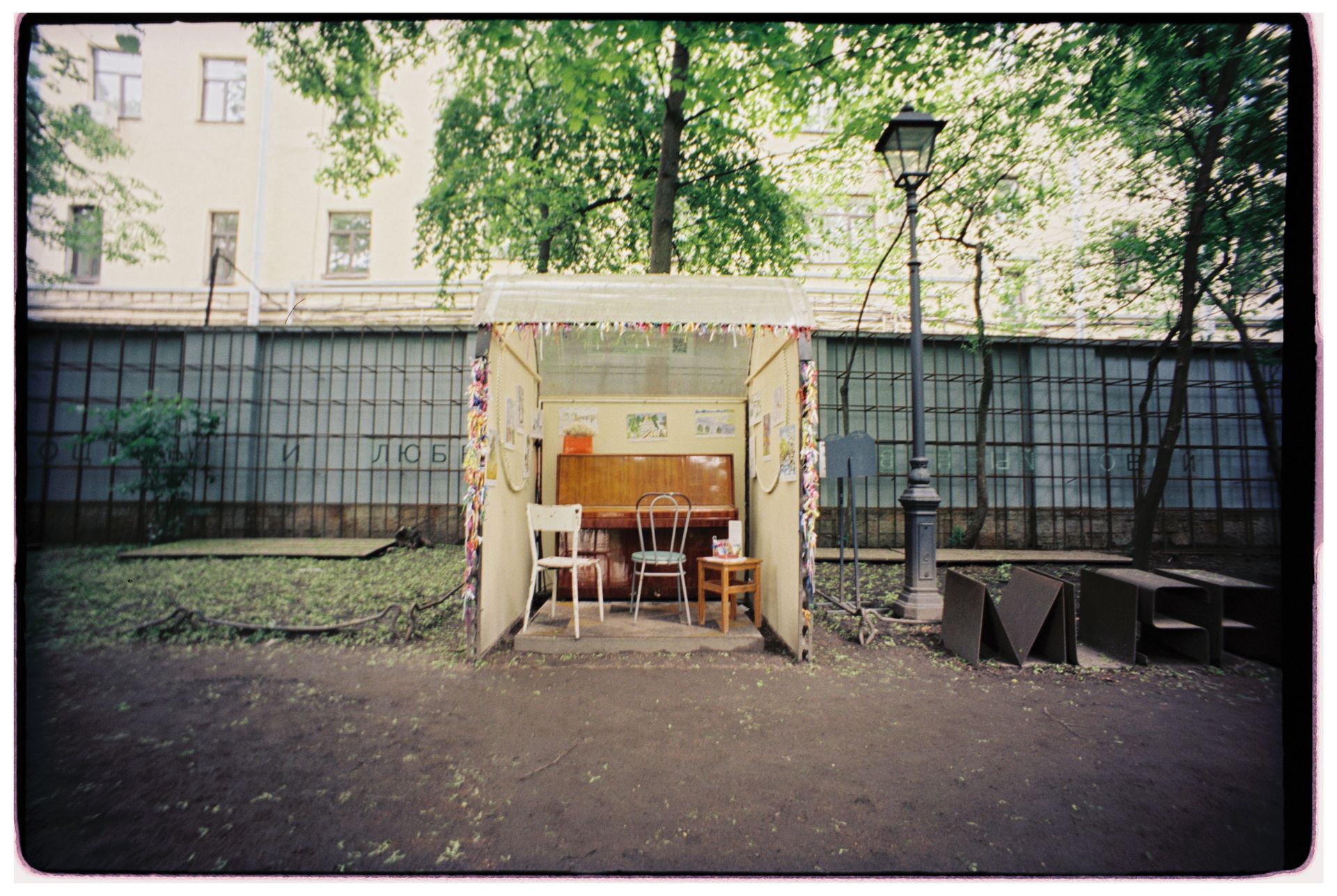 A cozy outdoor cafe with chairs and tables under summer trees.
