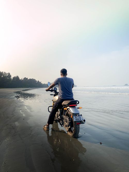 Free A motorcyclist rides along a serene beach during the day, creating a moment of adventure and tranquility. Stock Photo