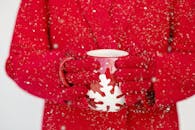 白雪皑皑的冬季，双手戴着红手套，拿着节日雪花杯