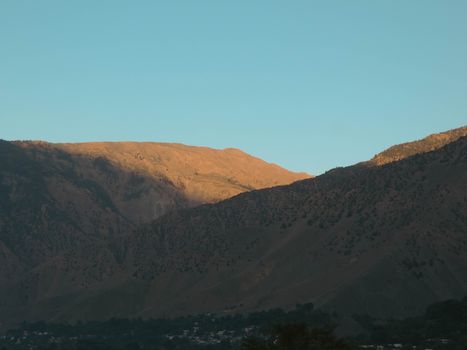 Peaceful mountain view at sunrise with warm light and clear skies.