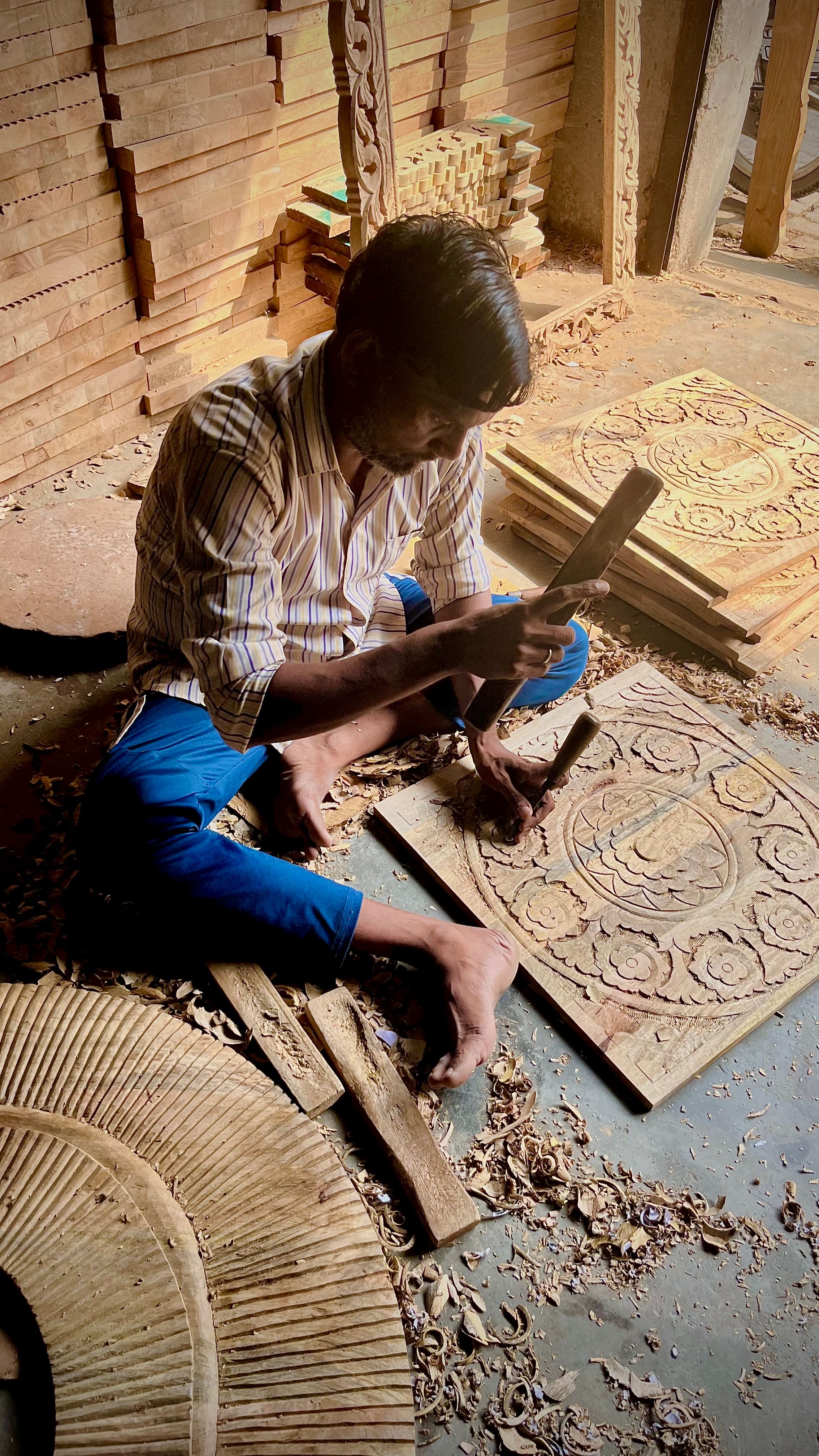 Indian artisan carefully shaping intricate wood carving by hand in Sarangpur