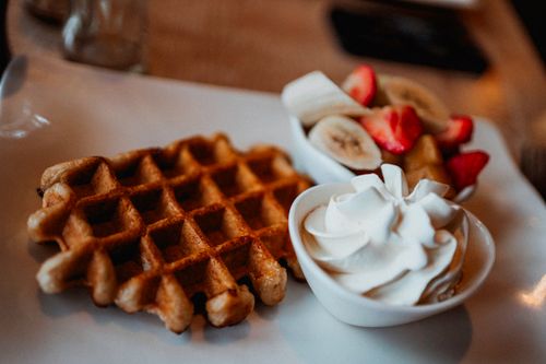 Free Mouthwatering waffle served with fresh fruit and whipped cream on a plate. Stock Photo