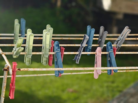 Colorful clothespins on a rusty clothesline against a blurred green background in New Zealand.