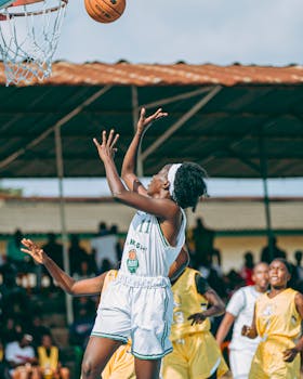 Exciting action shot of an athlete jumping to shoot a basketball during an outdoor game.