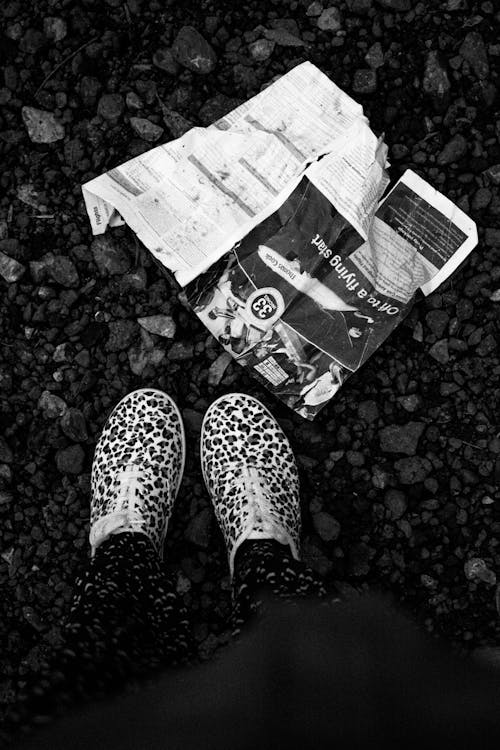 Grayscale Photography of Person Beside Flyer on Ground