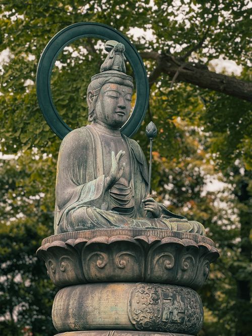 Free Peaceful Buddha statue captured outdoors surrounded by lush greenery. Stock Photo