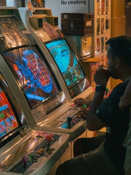 Vintage arcade gaming experience with a man playing retro video games in a classic gaming room.