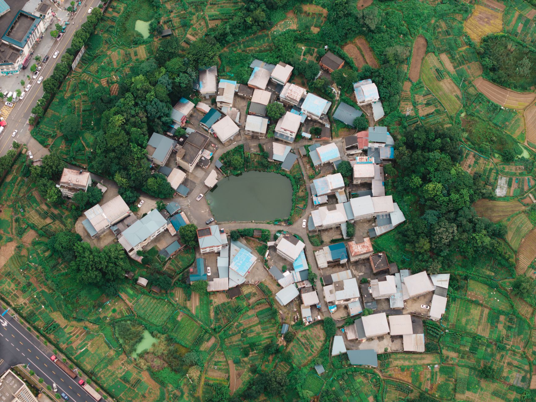 Scenic aerial view of a rural village surrounded by green fields and trees.
