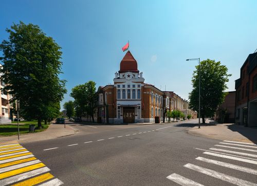 Free An empty street featuring a historic building with a red flag under a clear sky. Stock Photo