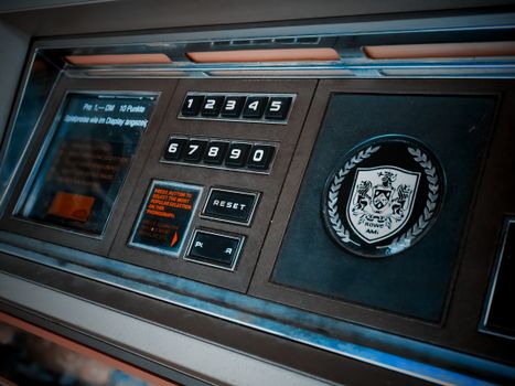 Close-up of a vintage arcade machine control panel with numeric keypad and emblem.