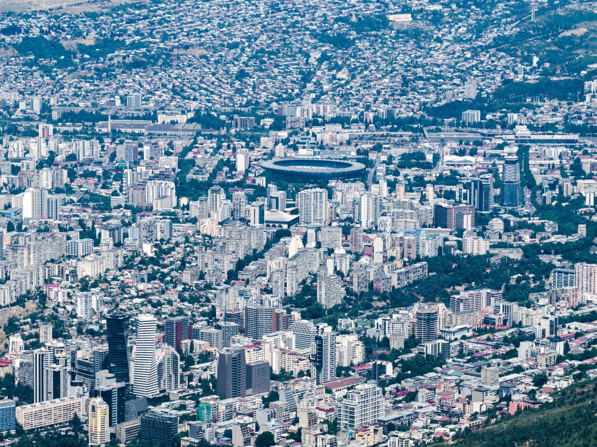 Explore the expansive urban landscape of Tbilisi, Georgia from above, showcasing diverse architecture.