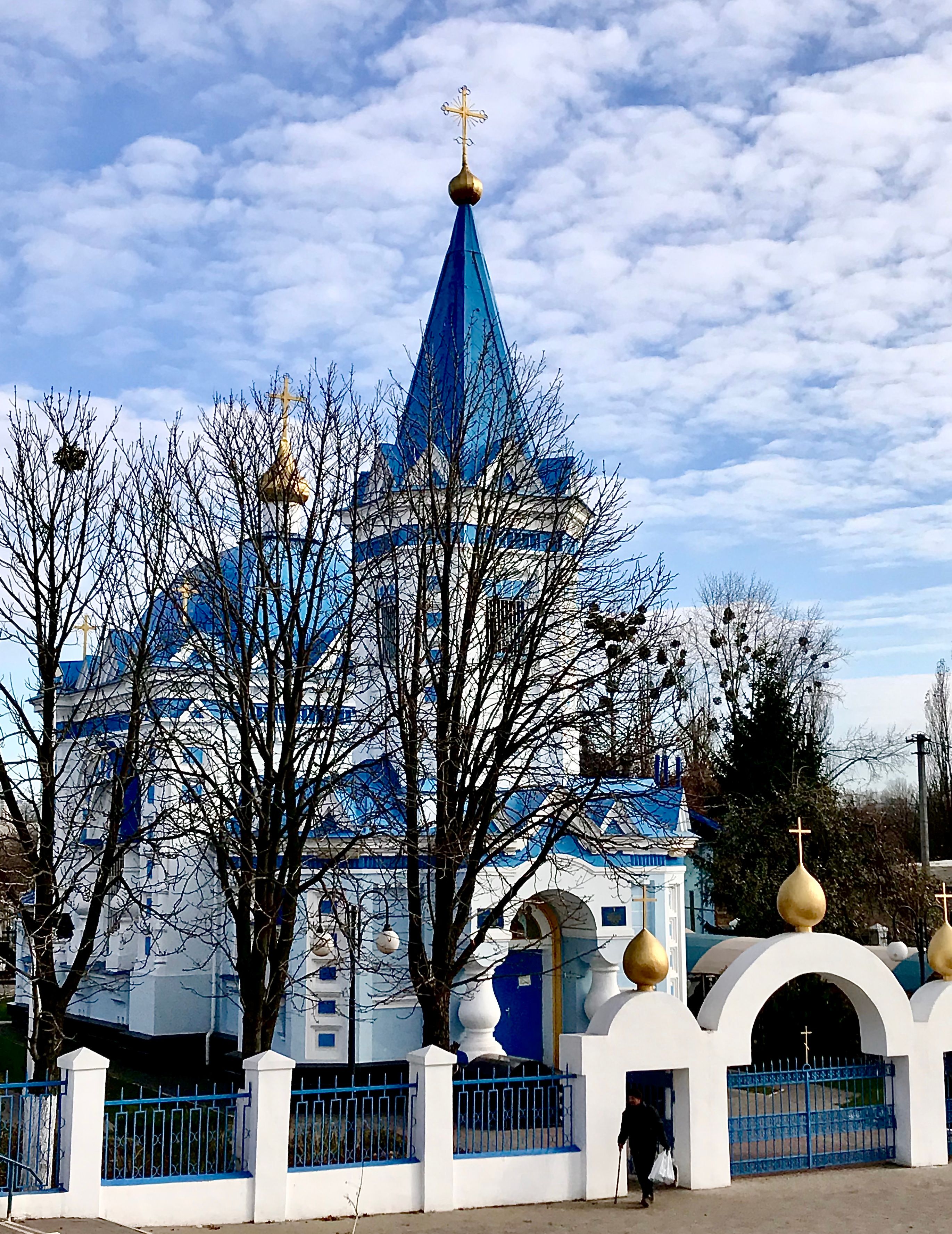 Stunning blue church with golden domes set against a bright winter sky, offering serene beauty.
