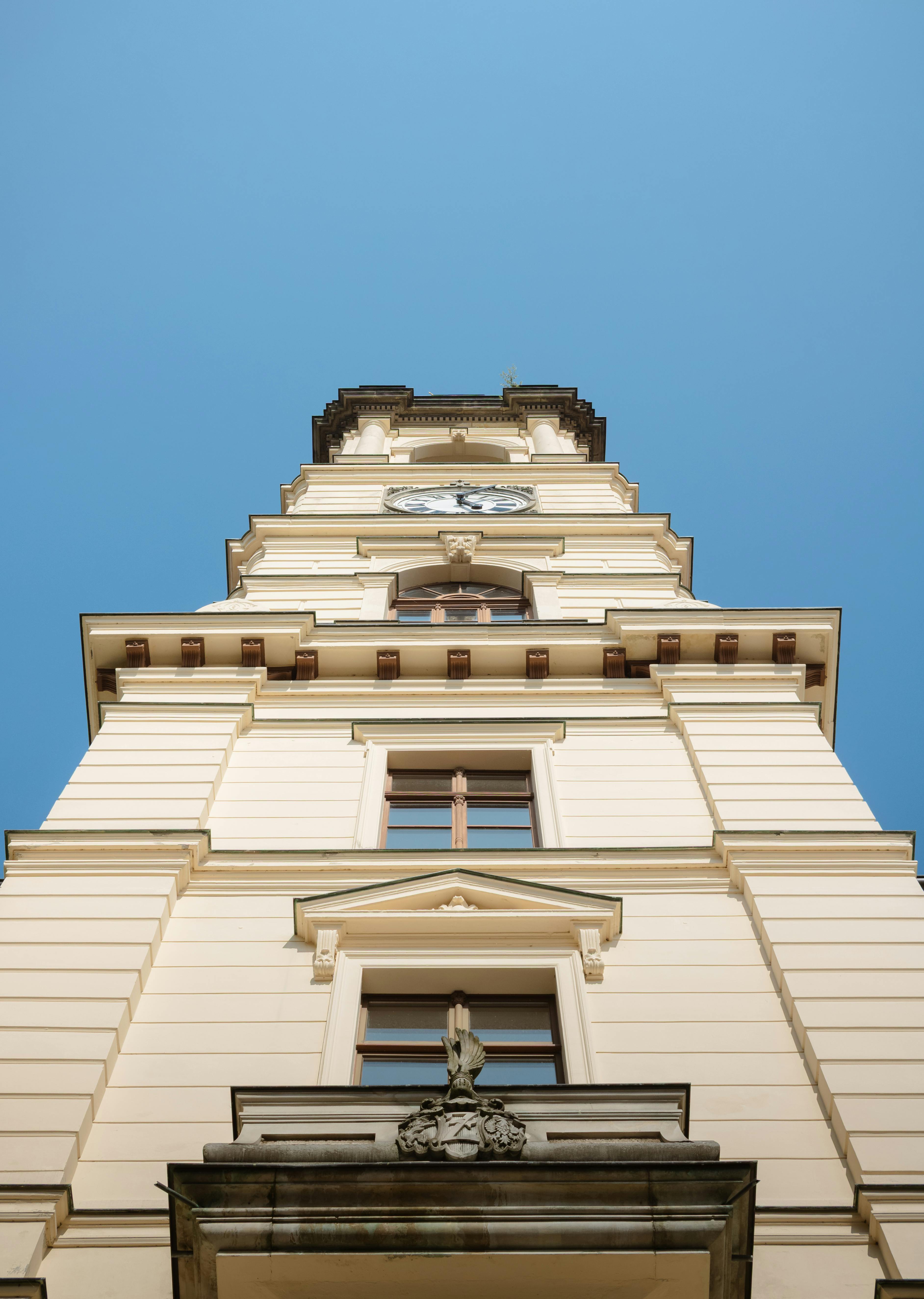 grátis Vista de cima da icônica torre do relógio em Zittau, exibindo seus detalhes arquitetônicos contra um céu claro. Foto profissional