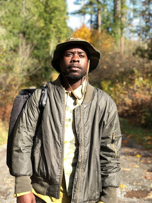 Man in Gray Leather Jacket Standing Near Plants