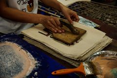 Artisan pressing a wooden block onto paper — photo by Đan Hà on Pexels